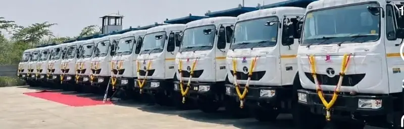 Row of new white trucks decorated with garlands at a fleet induction