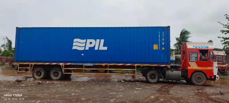 Blue 40ft container on a trailer pulled by a red truck