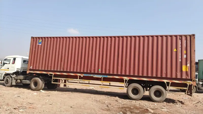 A 40ft container on a trailer standing on open ground under a clear sky