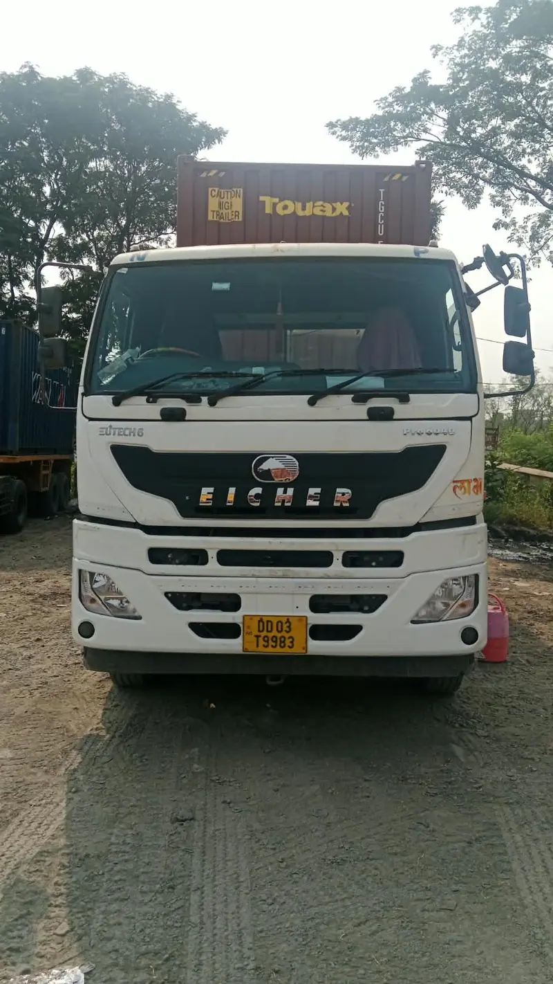 Truck carrying a container, parked among trees