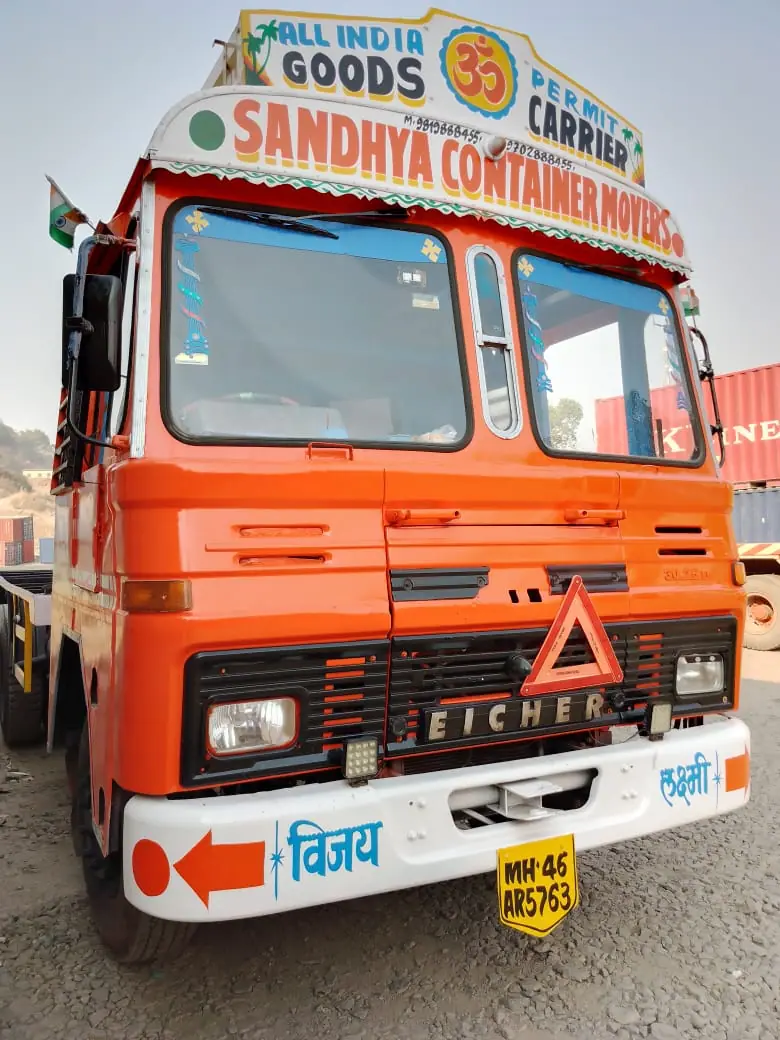 Front of an orange Sandhya Container Movers truck with hand-painted branding