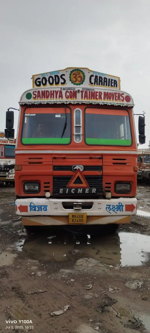 Orange Sandhya truck parked in a wet yard during the monsoon