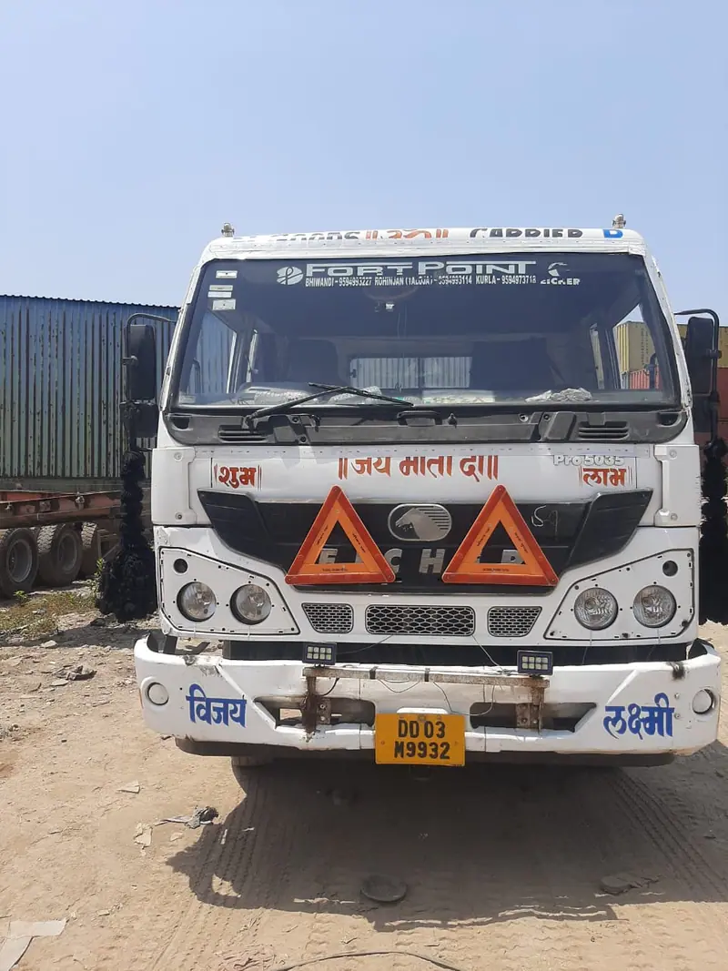 White truck parked in a yard with containers in the background